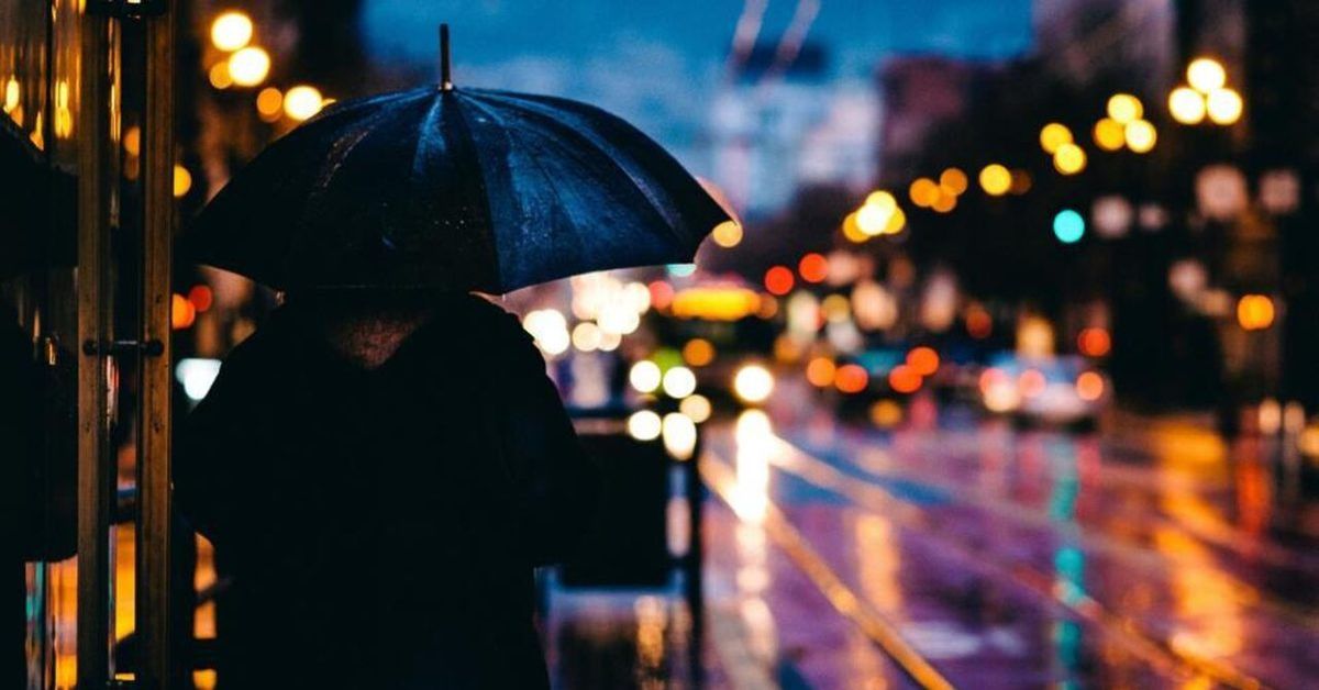 Wie ein krankes System unser Gehirn zerstört Mensch im Regen in einer nächtlichen Großstadt – Sinnbild für Dauerstress und mentale Überlastung