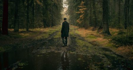 Mensch geht allein durch einen dunklen Waldweg – Symbol für den Weg aus chronischem Schmerz