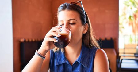 Frau trinkt Softdrink – hoher Zuckerkonsum kann Stoffwechsel, Bauchfett und Entzündungen fördern